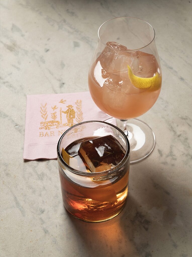 Two drinks from a Santa Fe bar sit on a marble table with a pink napkin to the left of the glasses.