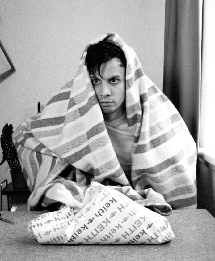A man sits wrapped in a towel in a black and white film project featured in Experiments in Cinema Festival.