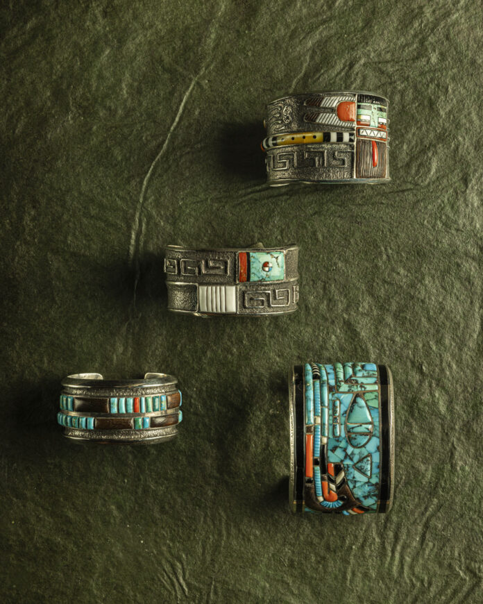 Jewelry pieces displayed against a textured green background, showcasing the artistic blend of traditional and modern elements.