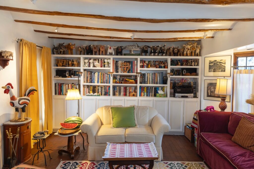 A living room set up with large shelves of books behind a white couch featuring a green pillow.