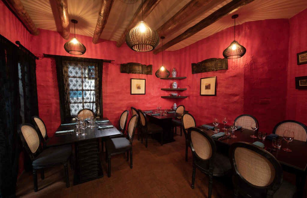 Alkeme restaurant in Santa Fe featuring an intimate dining space with bold red walls, rustic wood beams, and elegant table settings.