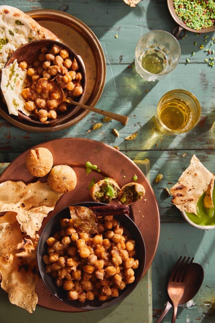 Savory Chana Masala A large brown plate holds a variety of holi food including Chana Masala in two separate bowls.