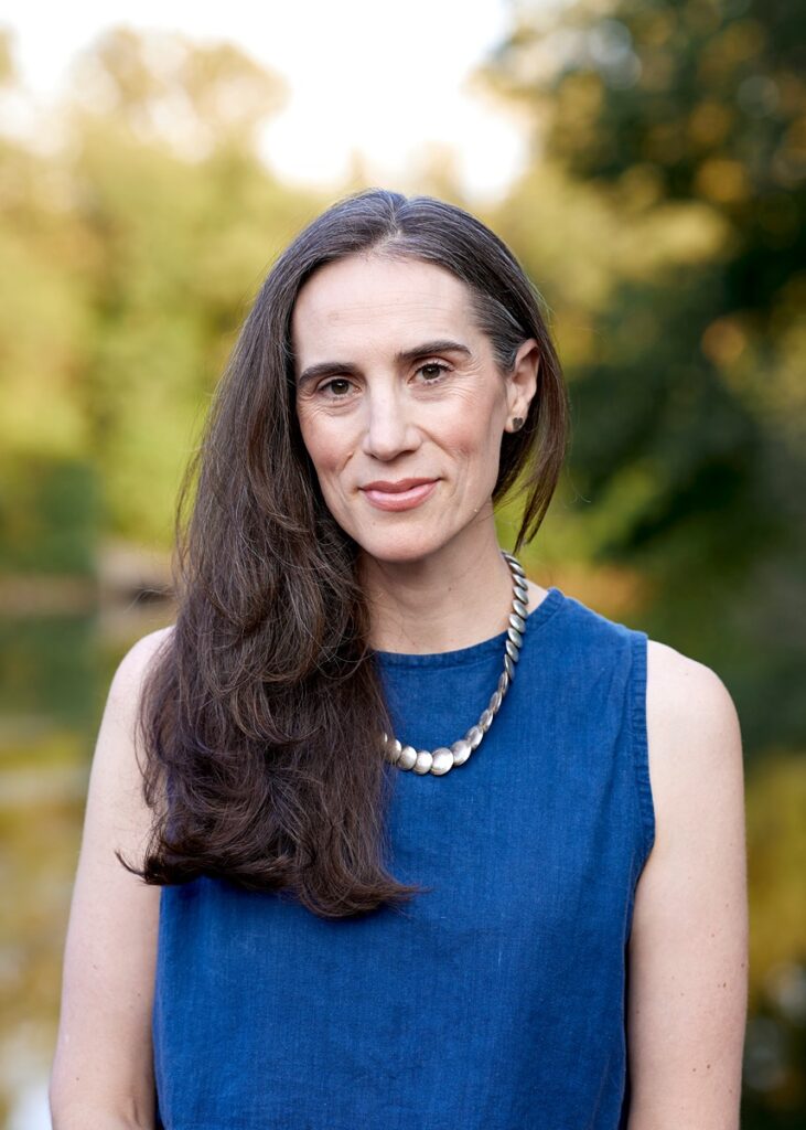 Cristin McKnight Sethi smiles while wearing a multicolored patterned dress or top.