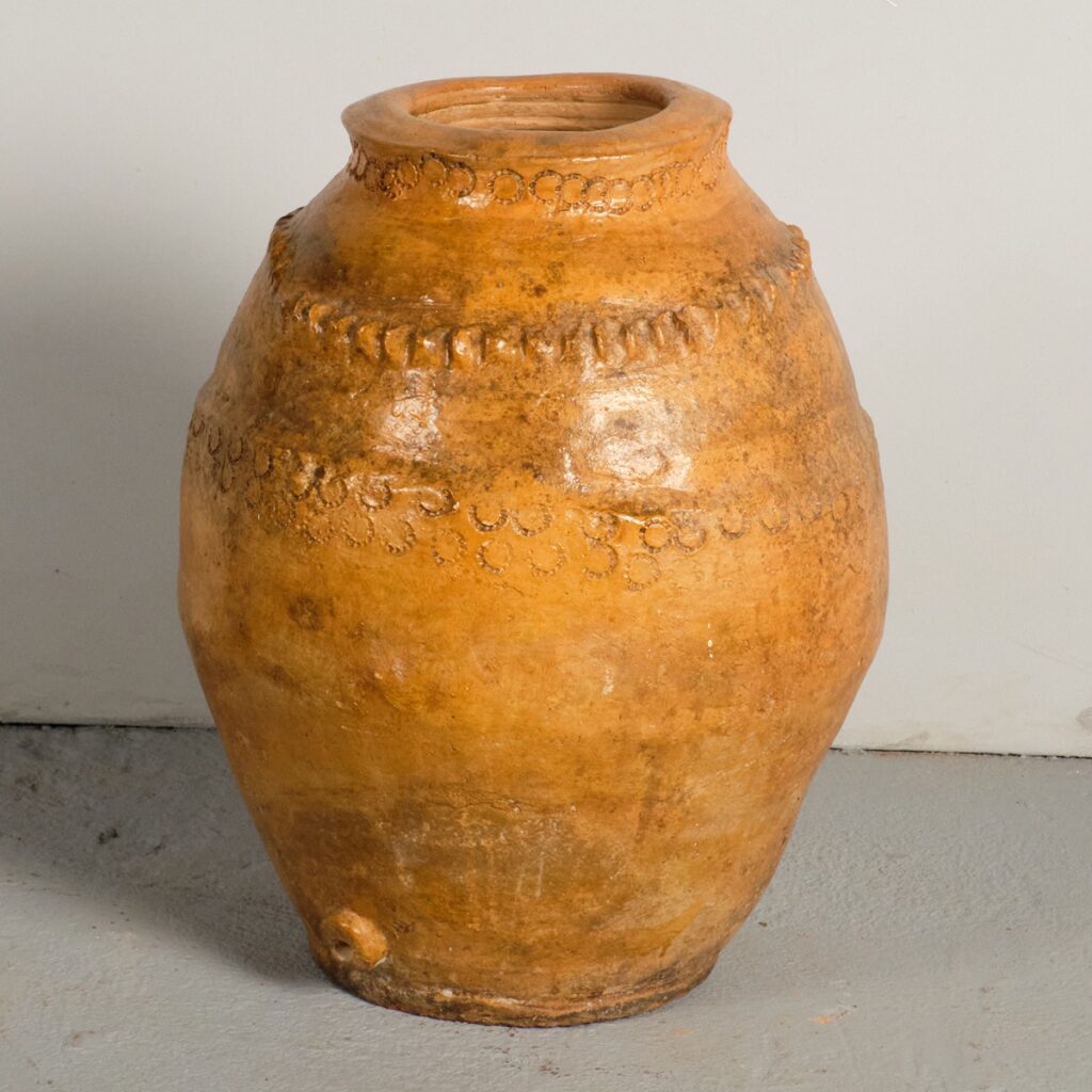 A glazed, ochre-colored antique oil jar from the late 18th to early 19th century.