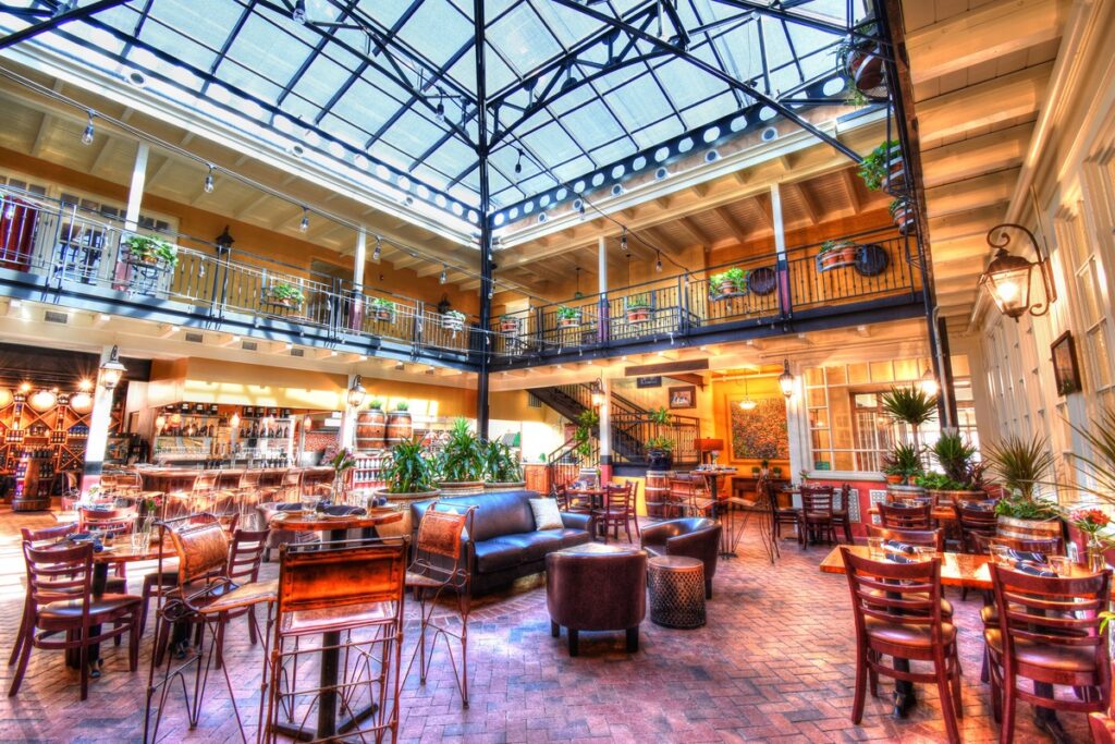 The bright and airy interior of Hervé Wine Bar in New Mexico, featuring multiple levels, dining tables, and a glass roof.