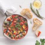 A plate of North African shakshouka staged with crusty bread.