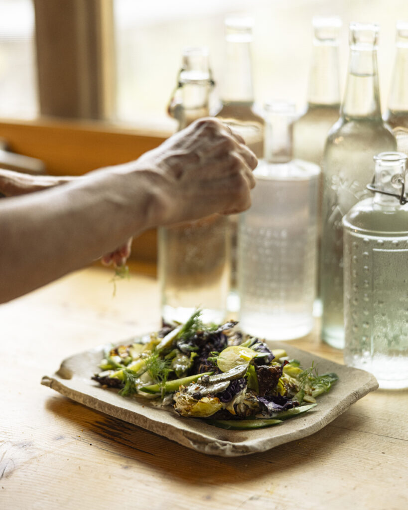 A colorful salad with roasted cabbage wedges, quick pickled cucumbers, sliced apples and pears, herbs, and cornichons, topped with a creamy dill vinaigrette.