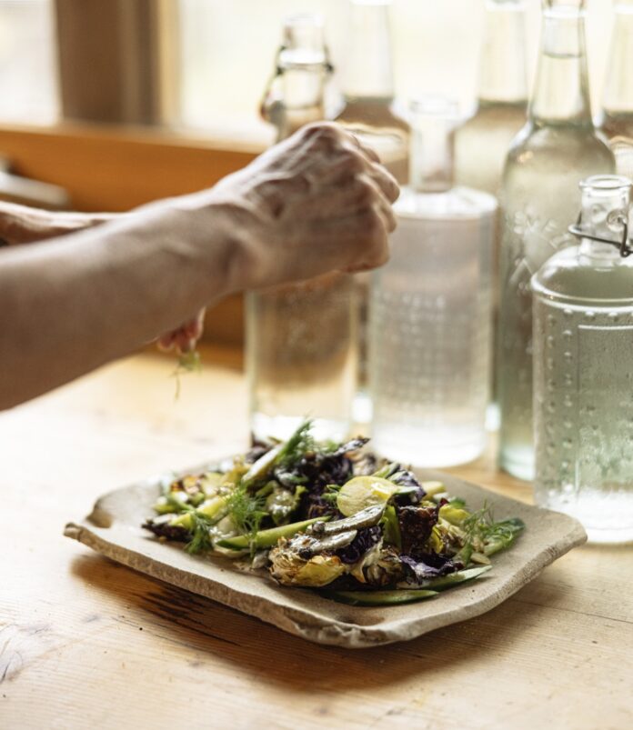 Roasted Cabbage Salad A person squeezes fresh juice over top of a Roasted Cabbage Salad sitting on a stone rectangular plate.