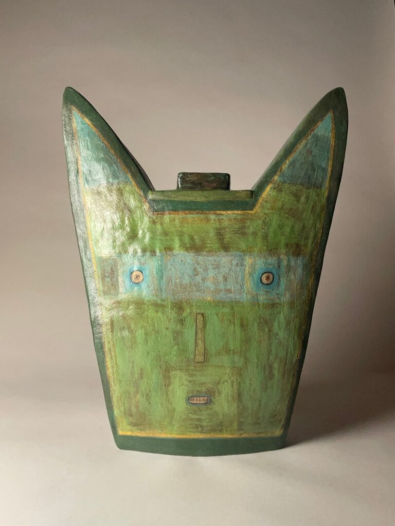 A green ceramic face jar by New Mexican artist Lisa Smith, featuring large pointed ears, painted facial features, and a textured surface.