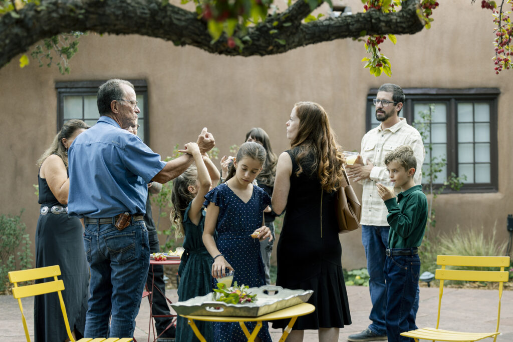 A diverse group of people gathers around a table, engaged in a creative discussion or activity related to art.