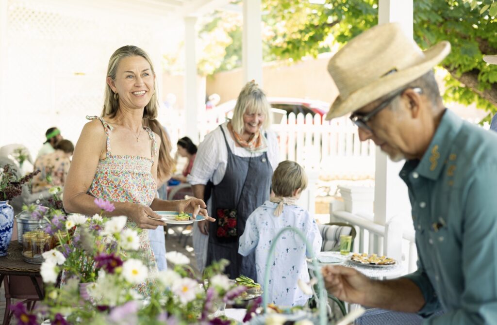 A man in a straw hat looks down at a table full of stone fruit food as a women smiles at him from down the table.