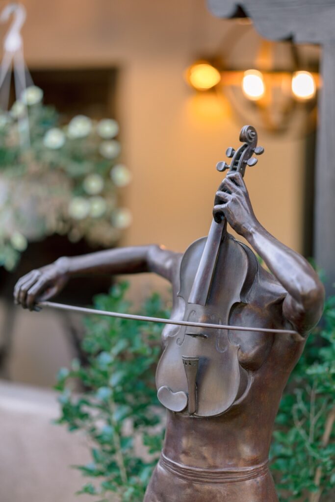 A bronze sculpture of a headless torso playing a violin.
