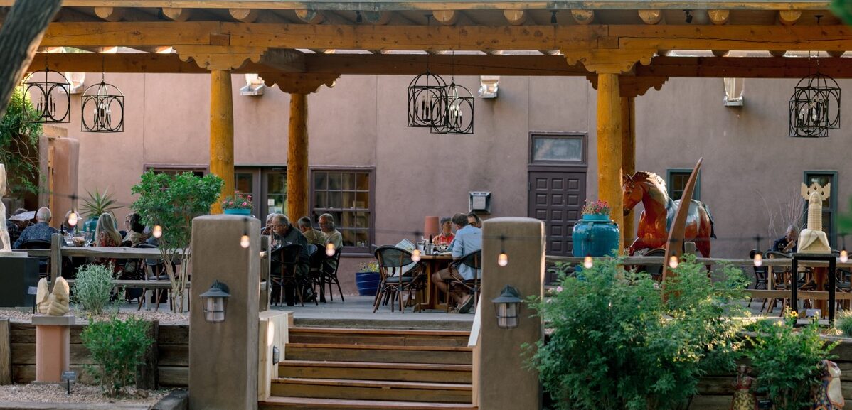 Outdoor dining patio with wooden beams and various sculptures.