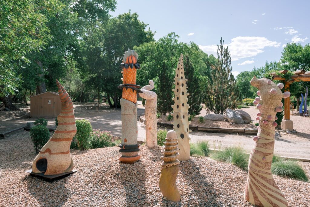 Several tall, abstract, colorful ceramic sculptures in a gravel garden.