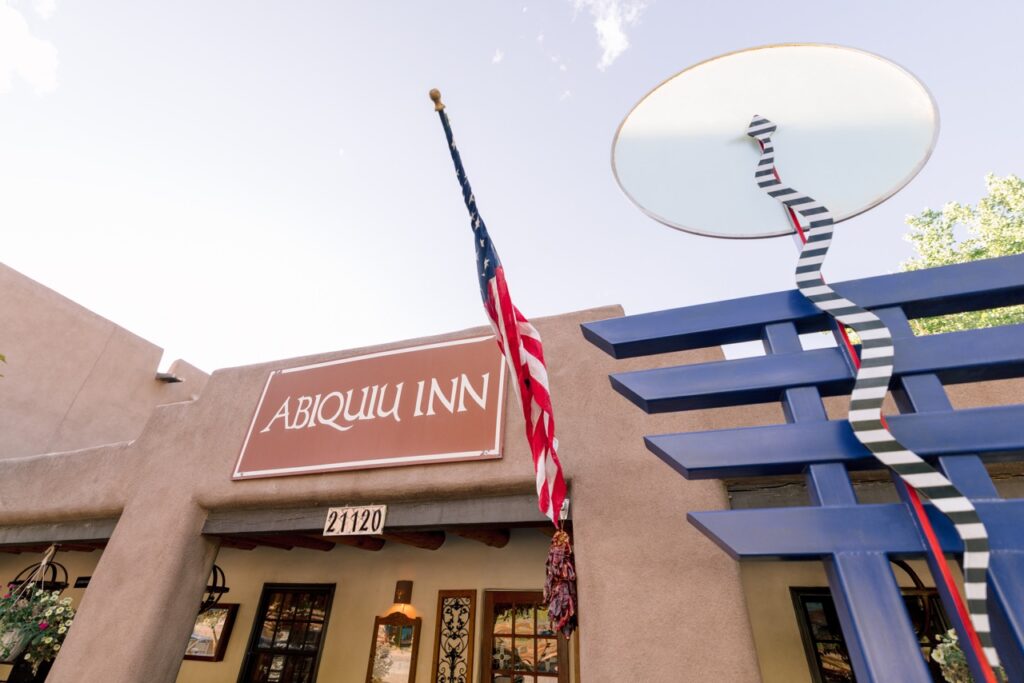 Exterior of Abiquiu Inn building with a sign and American flag.