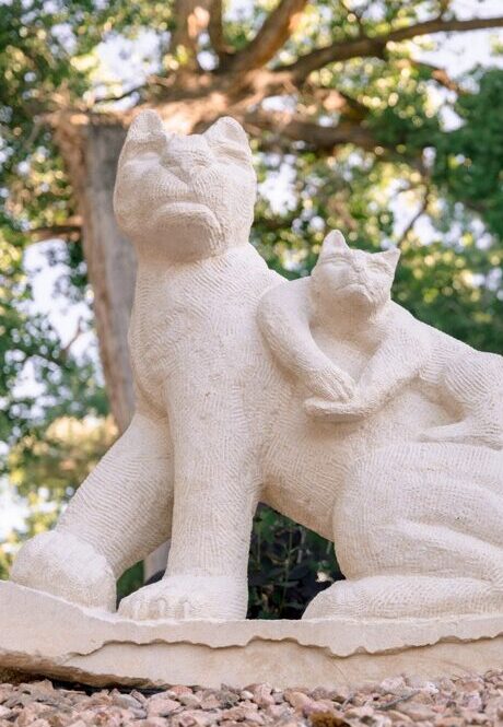 Stone sculpture of a large cat-like creature with a smaller one climbing on its back.