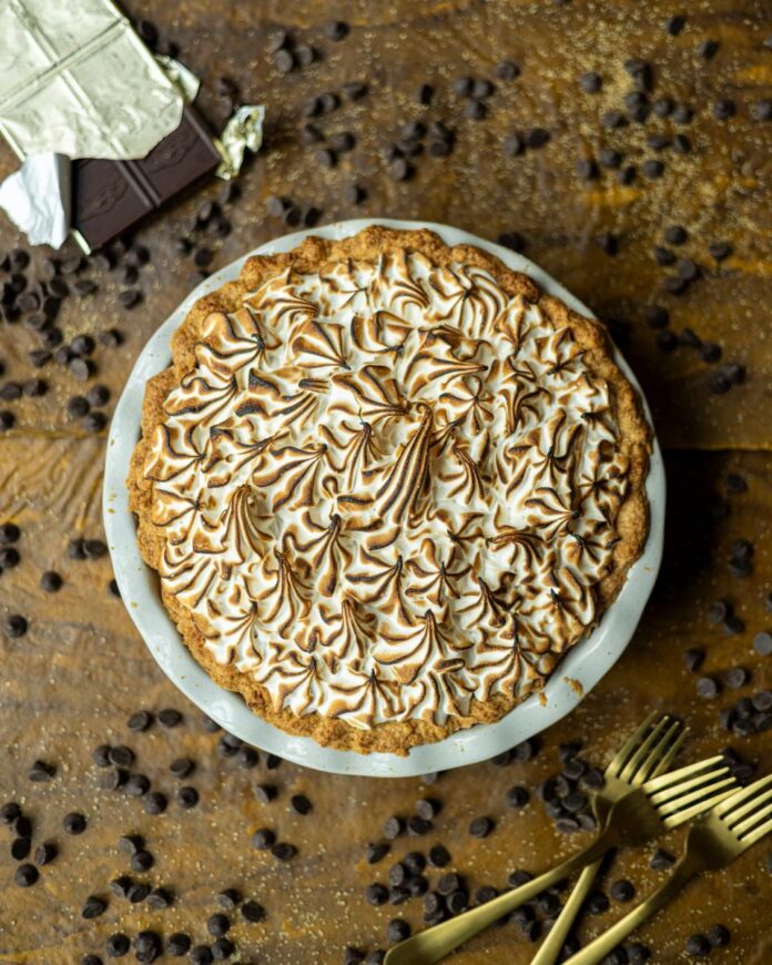Chocolate Pudding Pie A freshly baked chocolate pudding pie with toasted meringue on top is presented on a wooden surface.