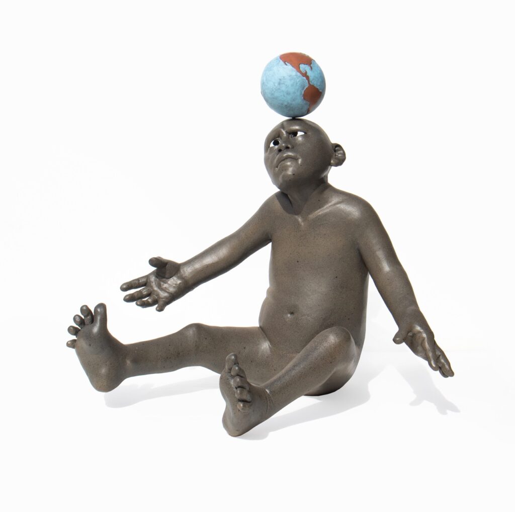 A monkey balances a ball on its head in sculpture form.