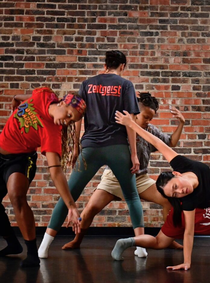 A Zeitgeist Dance Theatre dancer stands in the center of three other dancers stretched out around him.