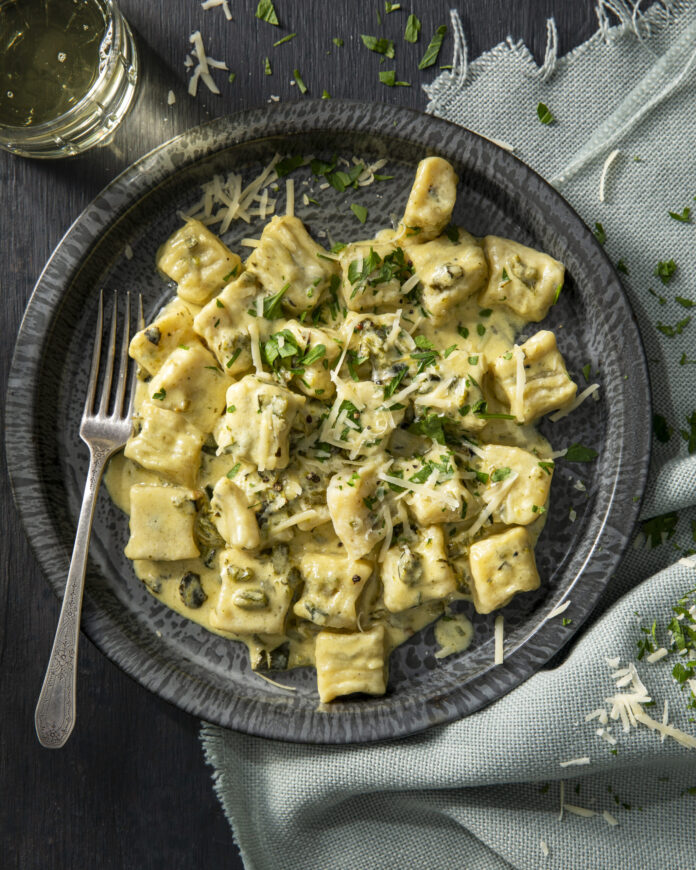 Ricotta Gnocchi with Roasted Green Chile Plated ricotta gnocchi in a roasted green chile sauce topped with parmesan cheese.