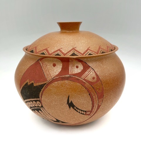 A brown pottery vase with a red and black design on it.