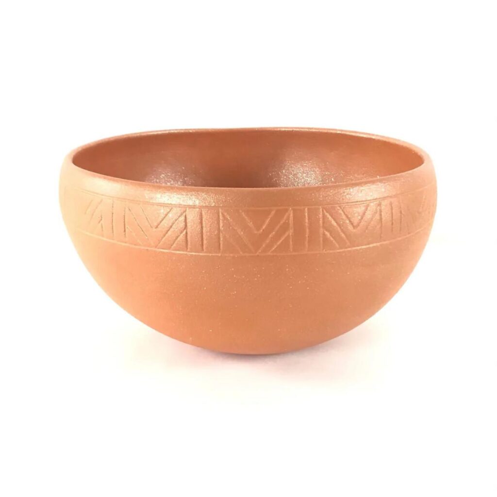 A tan-colored dough bowl with a linear etched pattern around the rim, made with traditional methods and micaceous clay.