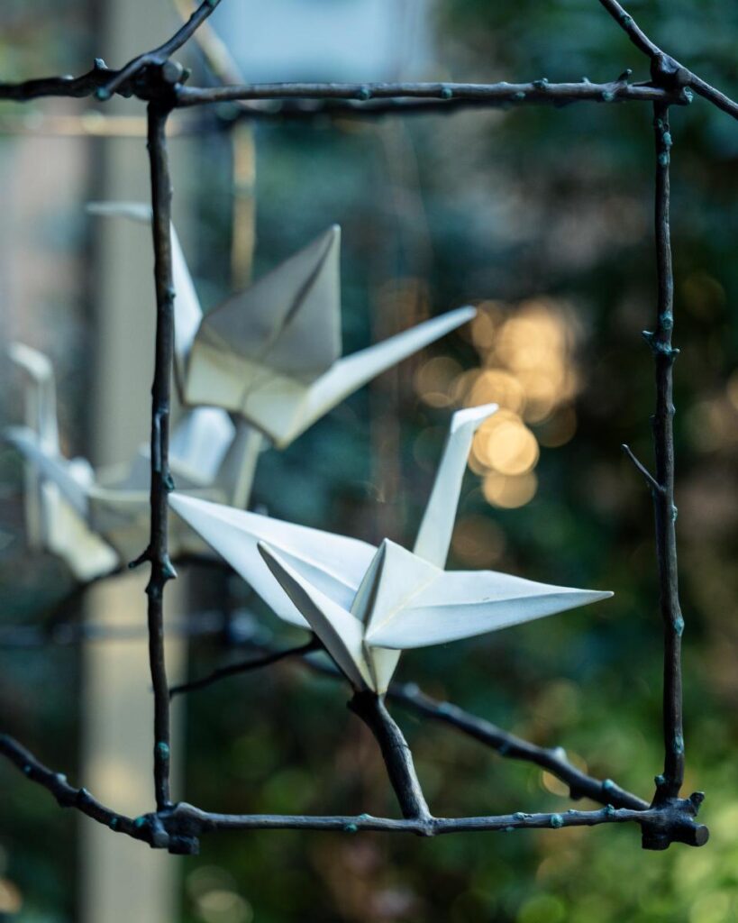 A close-up of two metal origami crane sculptures.