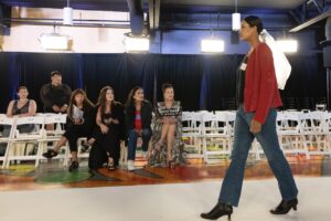 Native Fashion Week 2025 12 TABLE Magazine A woman in a red jacket walks down a runway.