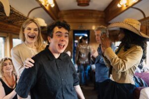 Native Fashion Week 2025 22 TABLE Magazine A group of people smile and clap on a bus.