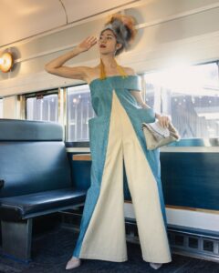 Native Fashion Week 2025 34 TABLE Magazine A woman in a blue and white jumpsuit poses on a bus.