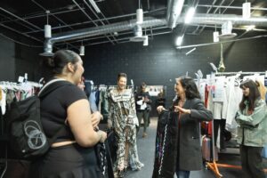 Native Fashion Week 2025 6 TABLE Magazine A group of people talk in a dressing space.