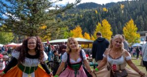 Three women dressed in german dresses with mountains in the back at RED RIVER OKTOBERFEST