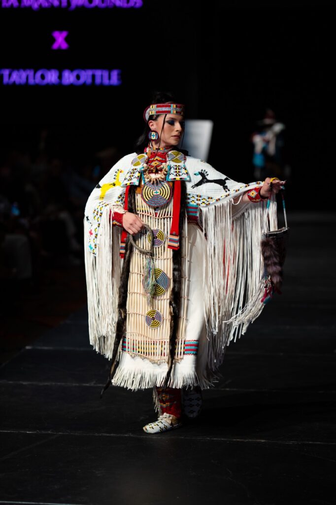 SWAIA Native Fashion Week 10 TABLE Magazine A woman in traditional native wear poses on stage.