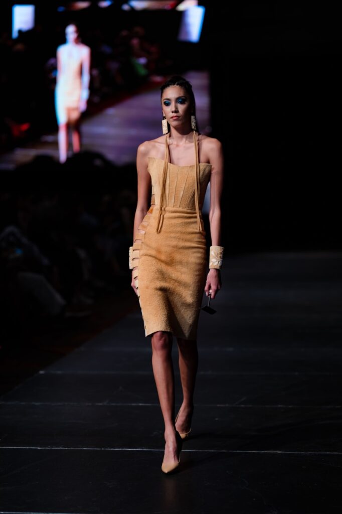 SWAIA Native Fashion Week 11 TABLE Magazine A woman in a khaki dress walks down a runway.