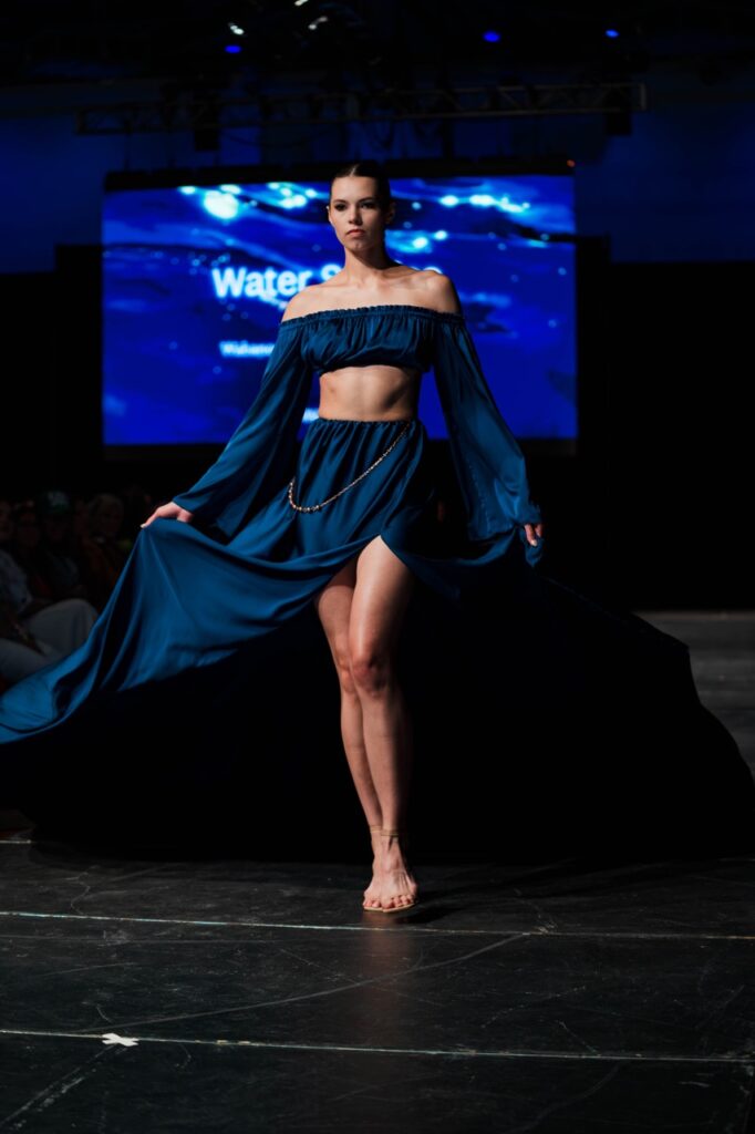 SWAIA Native Fashion Week 15 TABLE Magazine A woman in a two piece blue outfit poses on a runway.