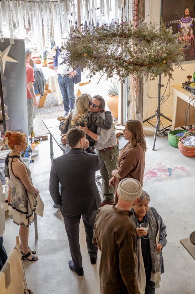 Spring Launch Party 11 TABLE Magazine A group of people talk as two of them hug.