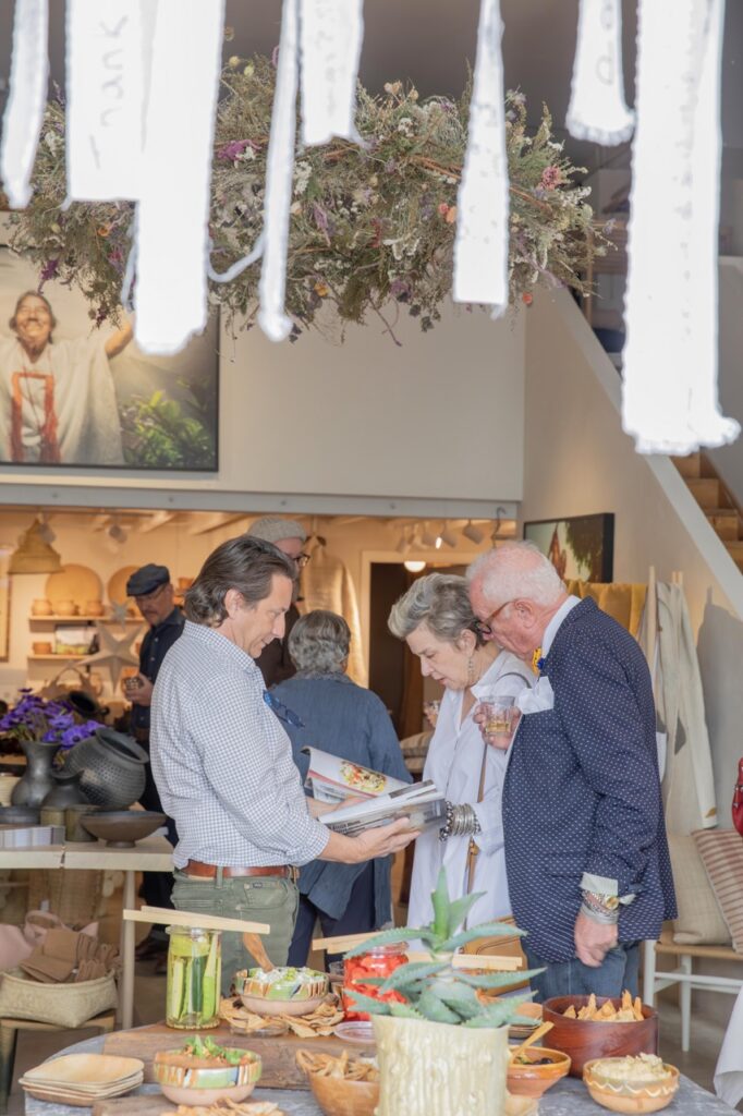 Spring Launch Party 16 TABLE Magazine Two men and a woman look at TABLE Magazine in a launch party space.