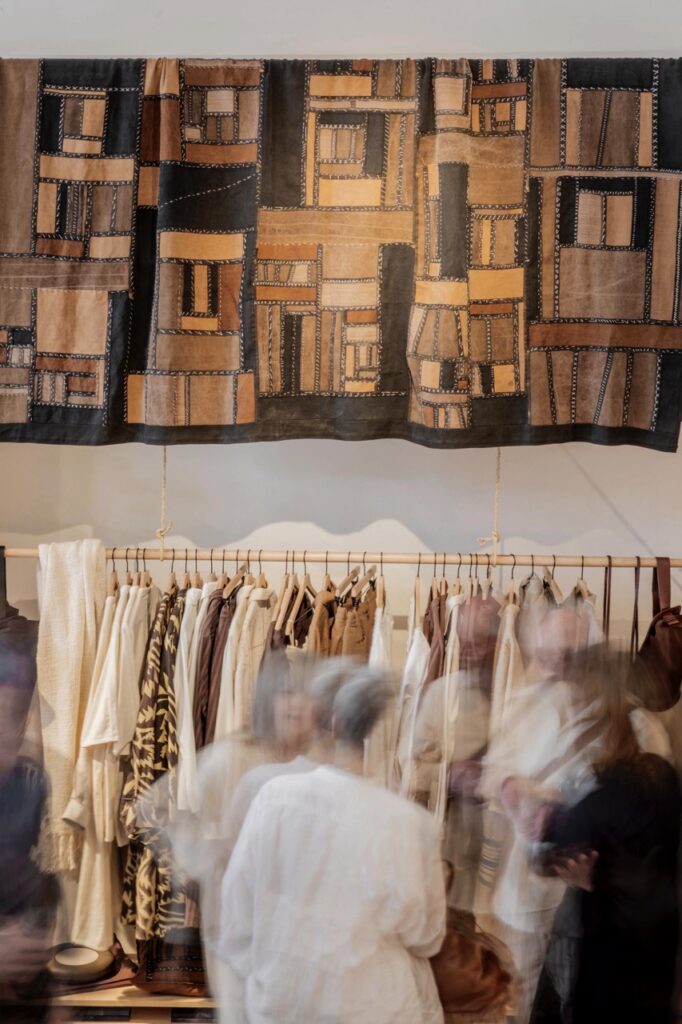 Spring Launch Party 18 TABLE Magazine People walking in front of a wall of clothes racks.