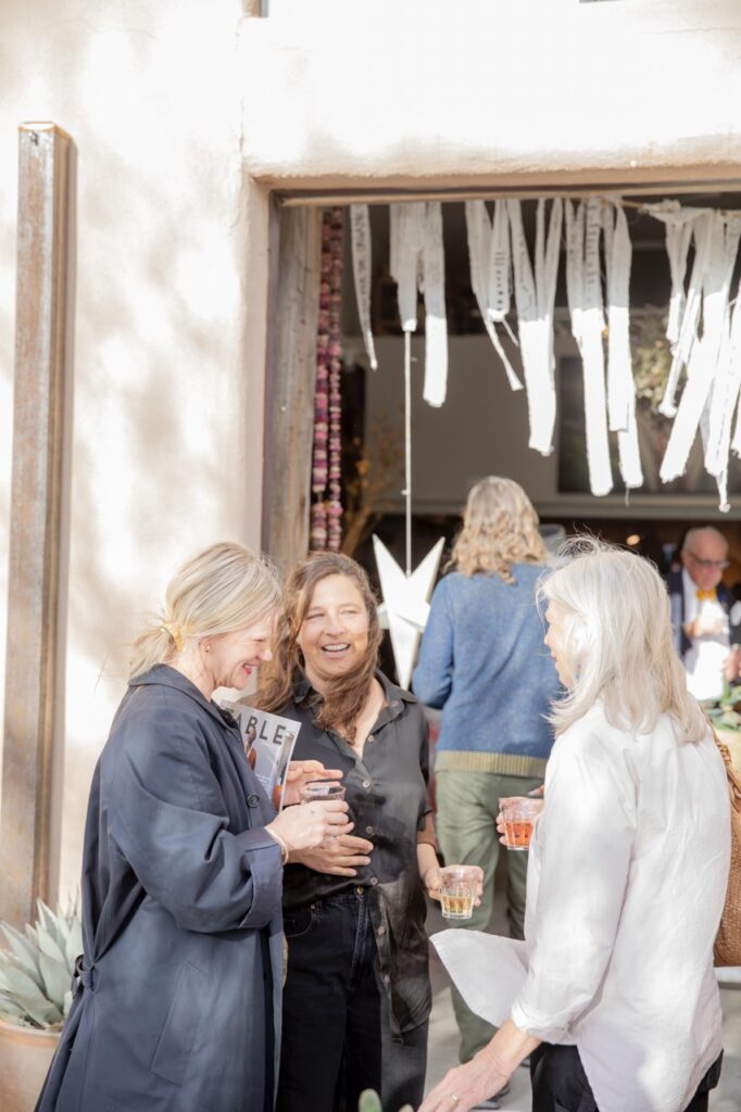 Spring Launch Party 24 TABLE Magazine Three women talk together with drinks in their hands.