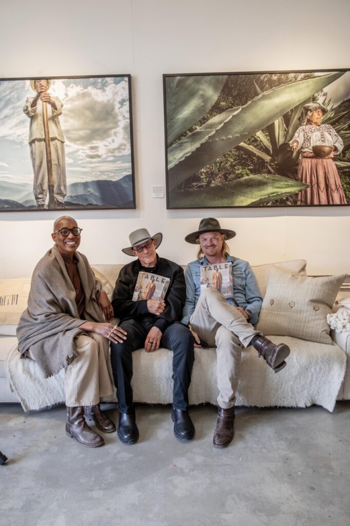 Spring Launch Party 29 TABLE Magazine Three people sit on a beige couch under large photos.