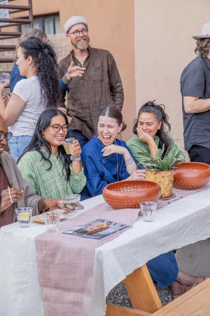 Spring Launch Party 33 TABLE Magazine Three people smile while sitting at a picnic table.