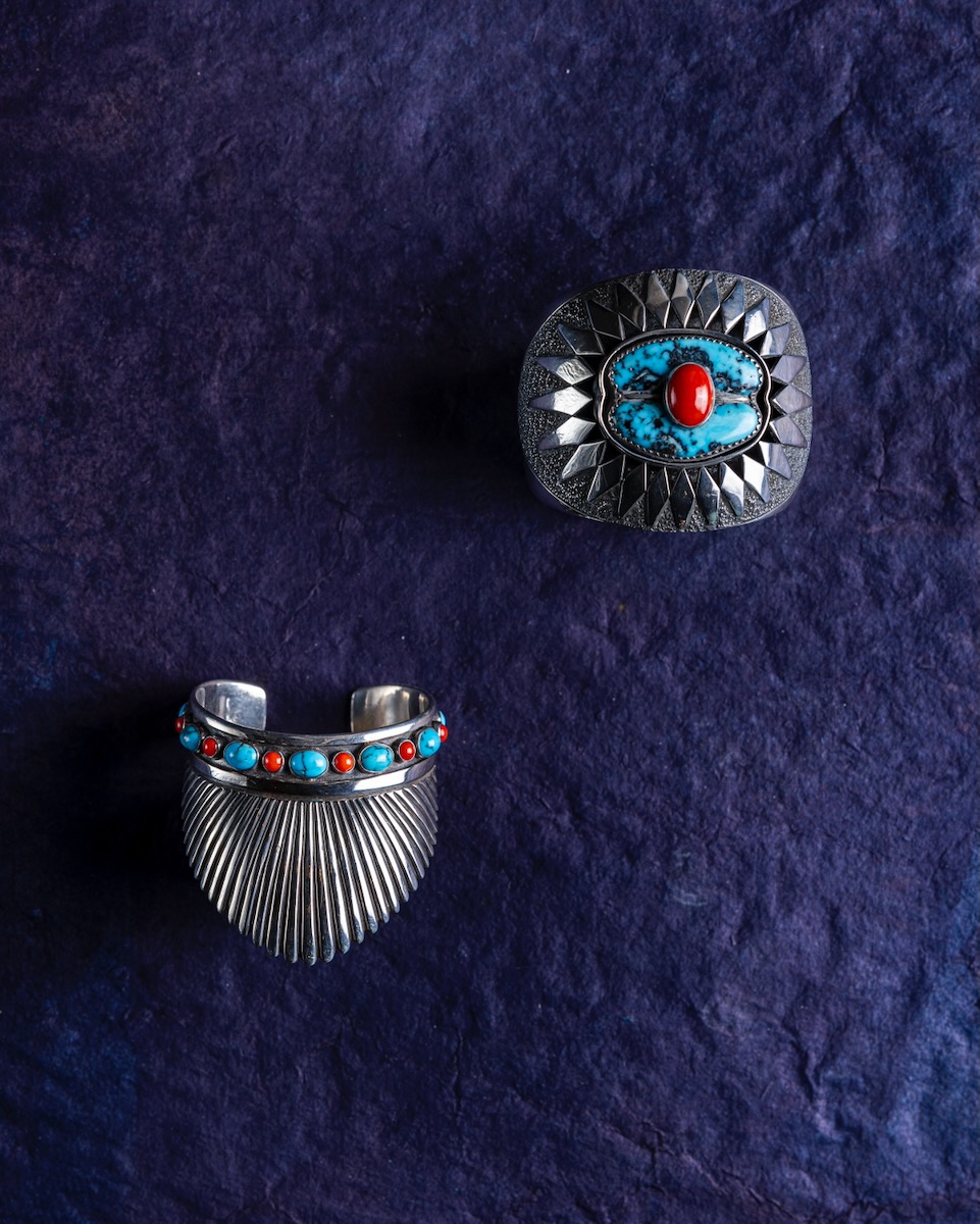 Two silver and turquoise cuffs sit on a dark blue background.