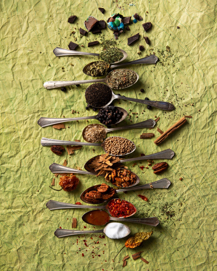 Pantry essentials showing spoons lined up with spices on green table