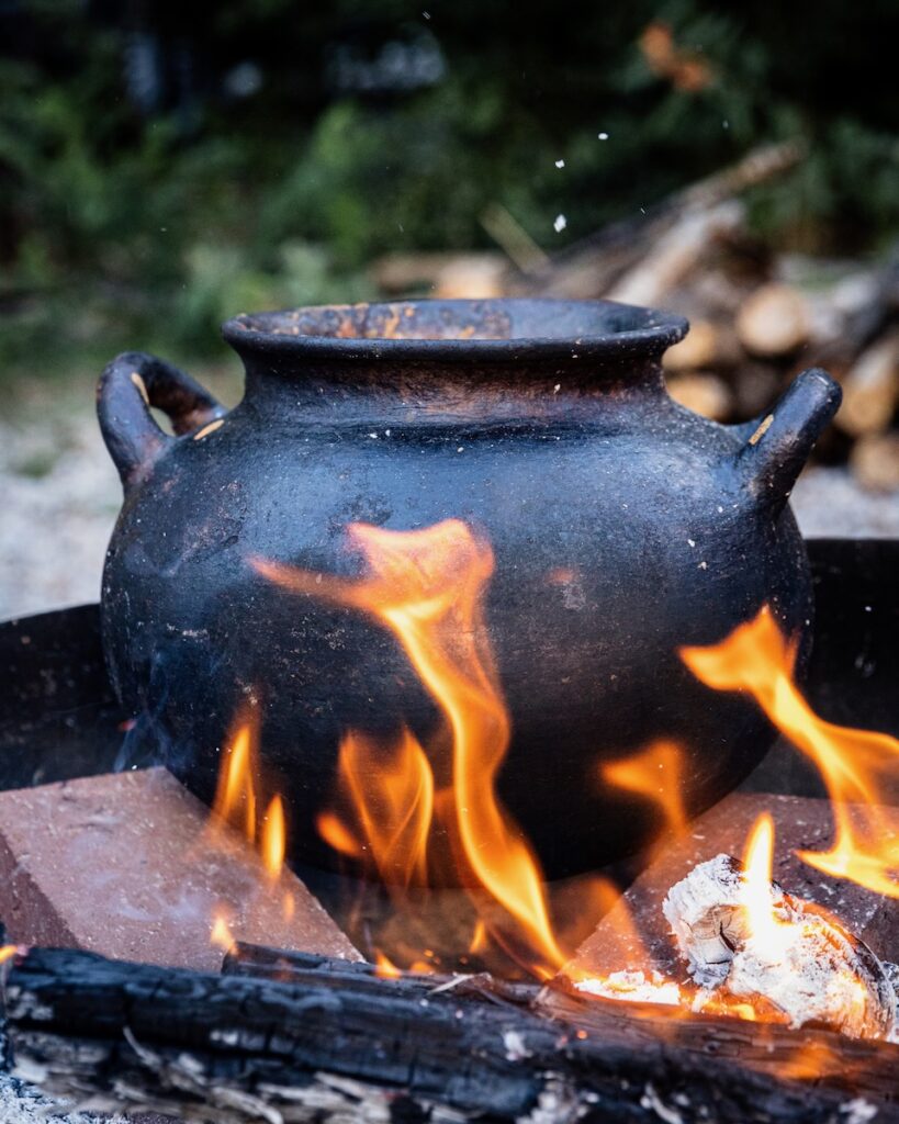 A large pot sitting in a fire cooking