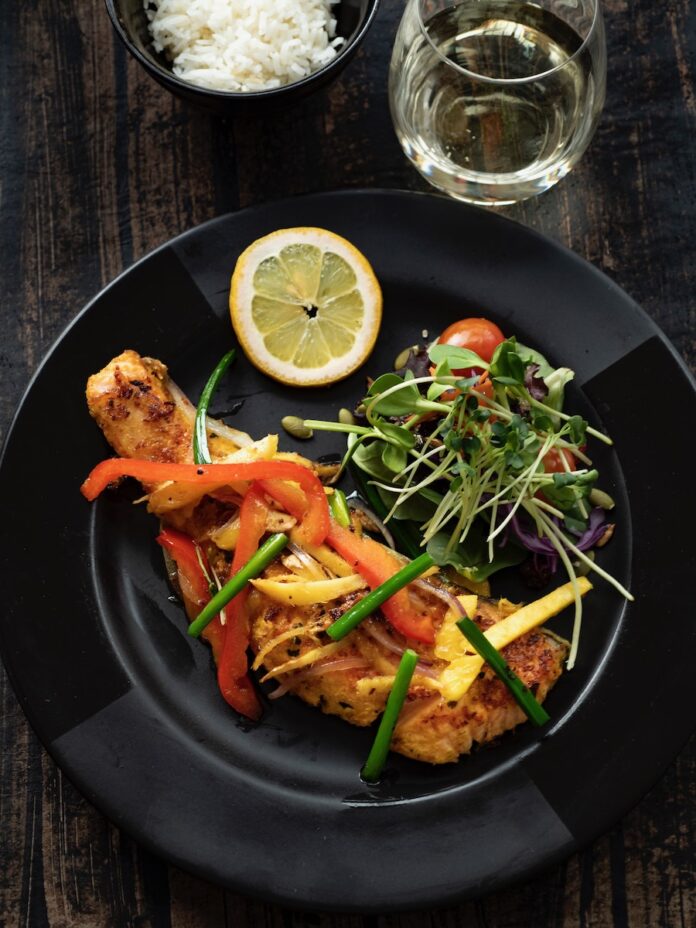 Wild-Caught Alaskan Salmon on black plate with greens.