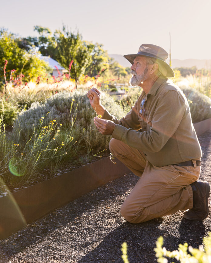 A man squats beside Los Poblanos' garden.