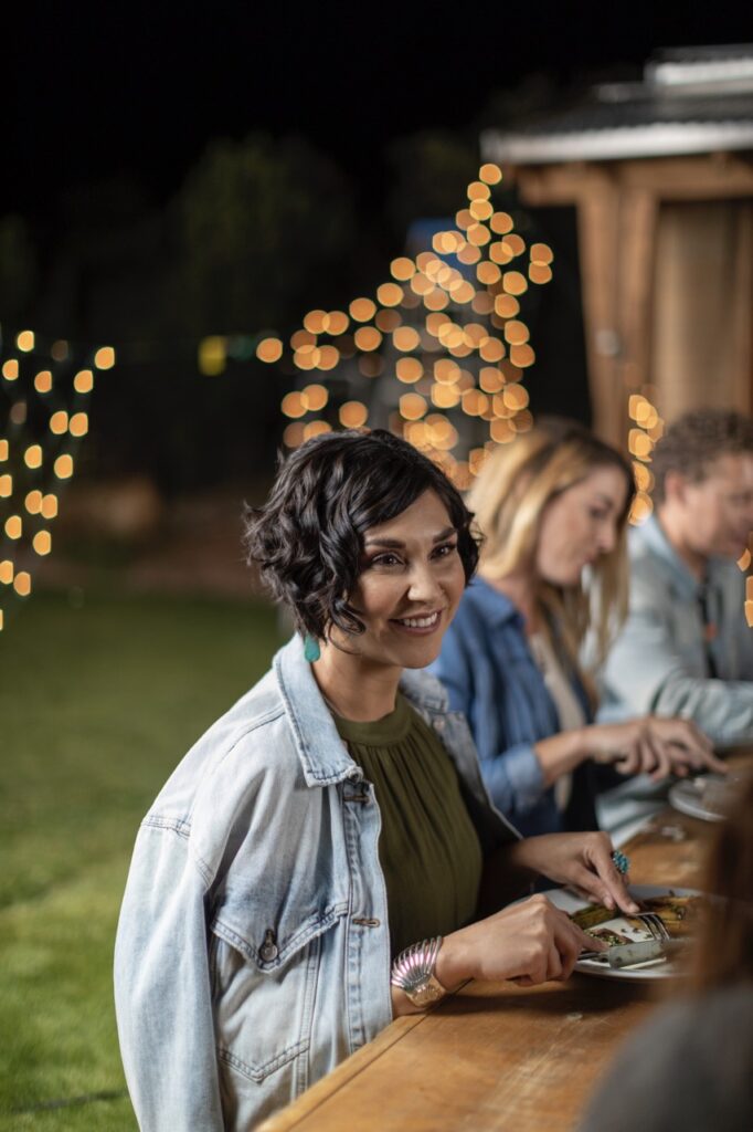 A woman smiles at an outdoor picnic table. 
