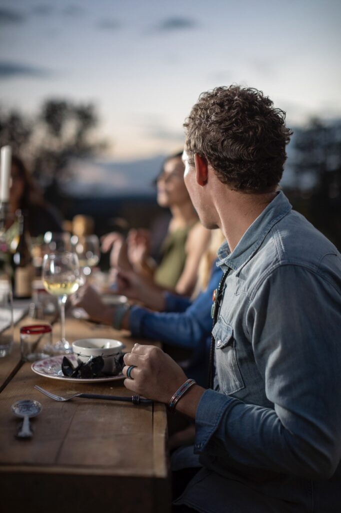 A man at a picnic table listens to conversation at the table.