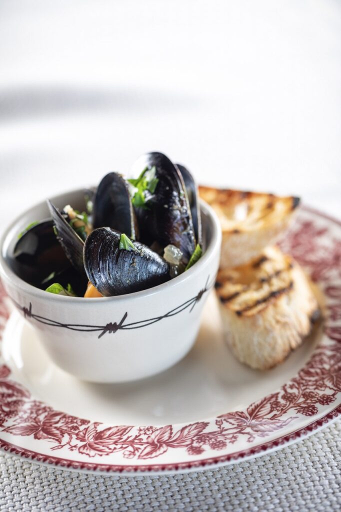 A bowl of mussels on a small plate.