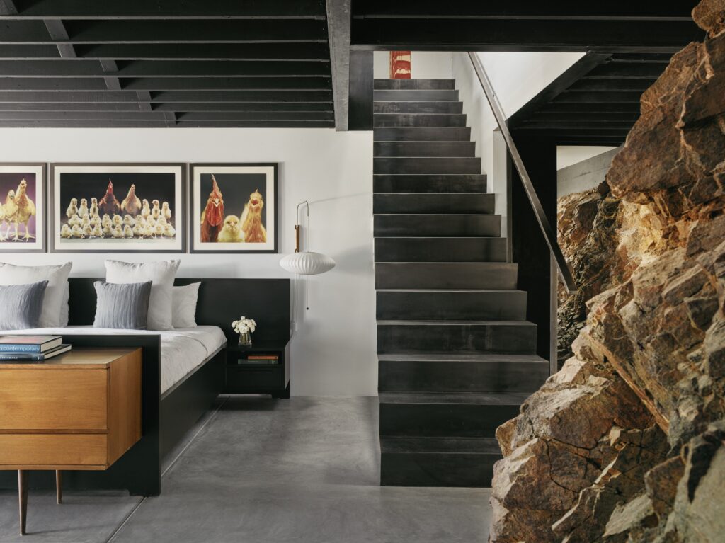 black staircase with bed to left with chicken posters on wall